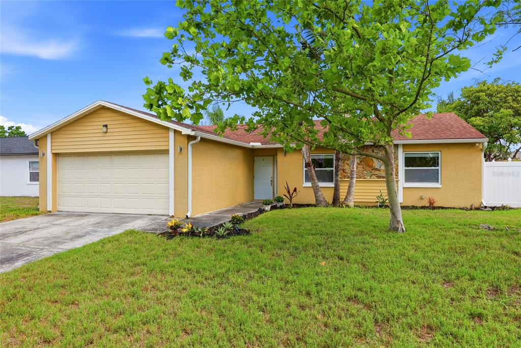 A yellow single-story house with a two-car garage and a concrete driveway at sunset — 8405 SOMERSET DRIVE, LARGO, FL