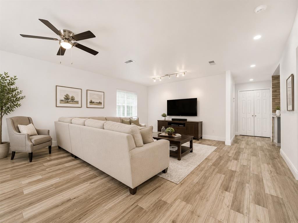 A living room features a beige sectional sofa, a dark wood media console, and wood-look flooring — 1044 NIN STREET, ORLANDO, FL