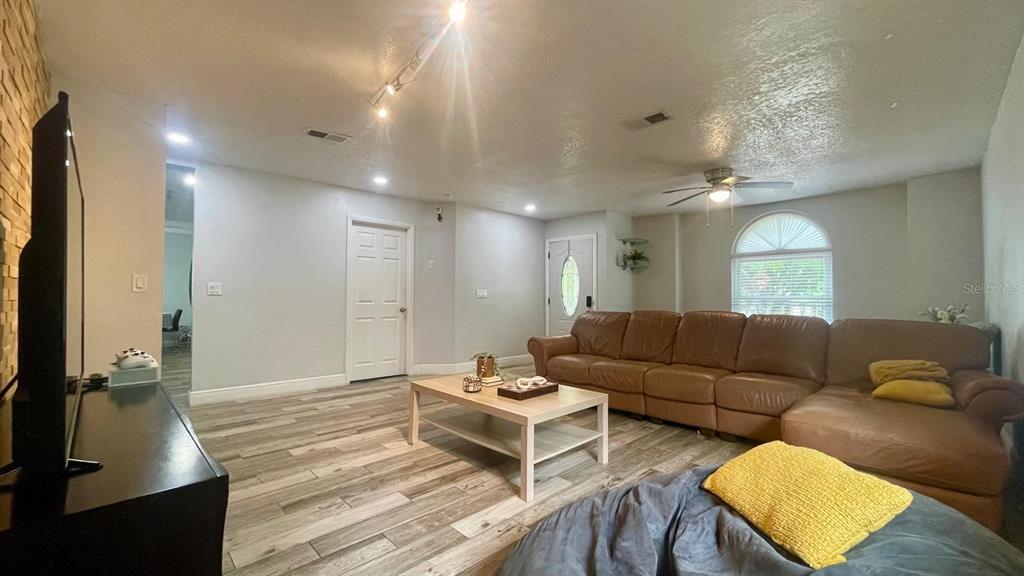 A living room features a brown sectional sofa, a coffee table, and wood-look tile flooring — 1044 NIN STREET, ORLANDO, FL