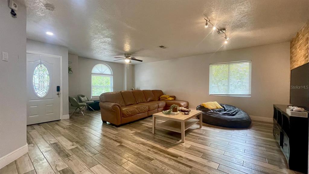 A living room features a brown leather sofa, a coffee table, and wood-look tile flooring — 1044 NIN STREET, ORLANDO, FL