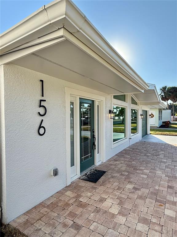 A white stucco building exterior features a green front door, black house numbers, and pavers — 156 N BLVD OF THE PRESIDENTS, SARASOTA, FL