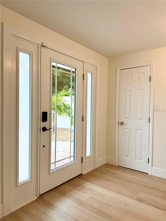 An entryway features a white front door with sidelights and light wood-look flooring — 156 N BLVD OF THE PRESIDENTS, SARASOTA, FL