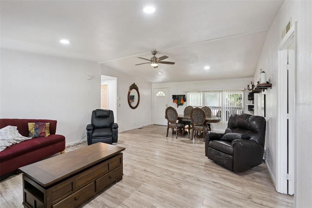A living and dining area features light wood-look flooring, a ceiling fan, and neutral walls — 2051 TRAIL CUT ROAD, POLK CITY, FL