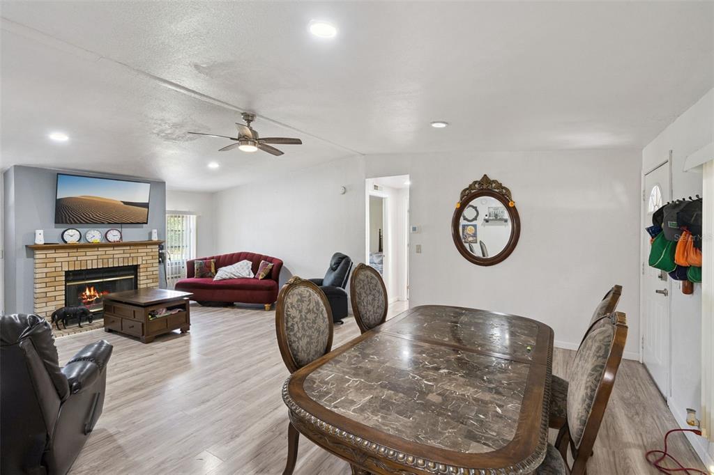 A living and dining area features a brick fireplace, marble-topped table, and light wood flooring — 2051 TRAIL CUT ROAD, POLK CITY, FL