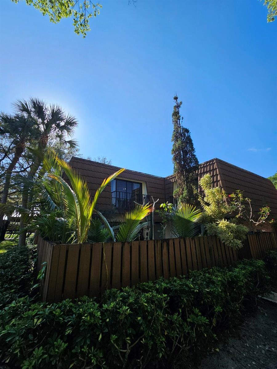 A two-story building with a brown shingled roof, balcony, and a wooden privacy fence — 209 Charter Way, West Palm Beach FL 33407, WEST PALM BEACH, FL