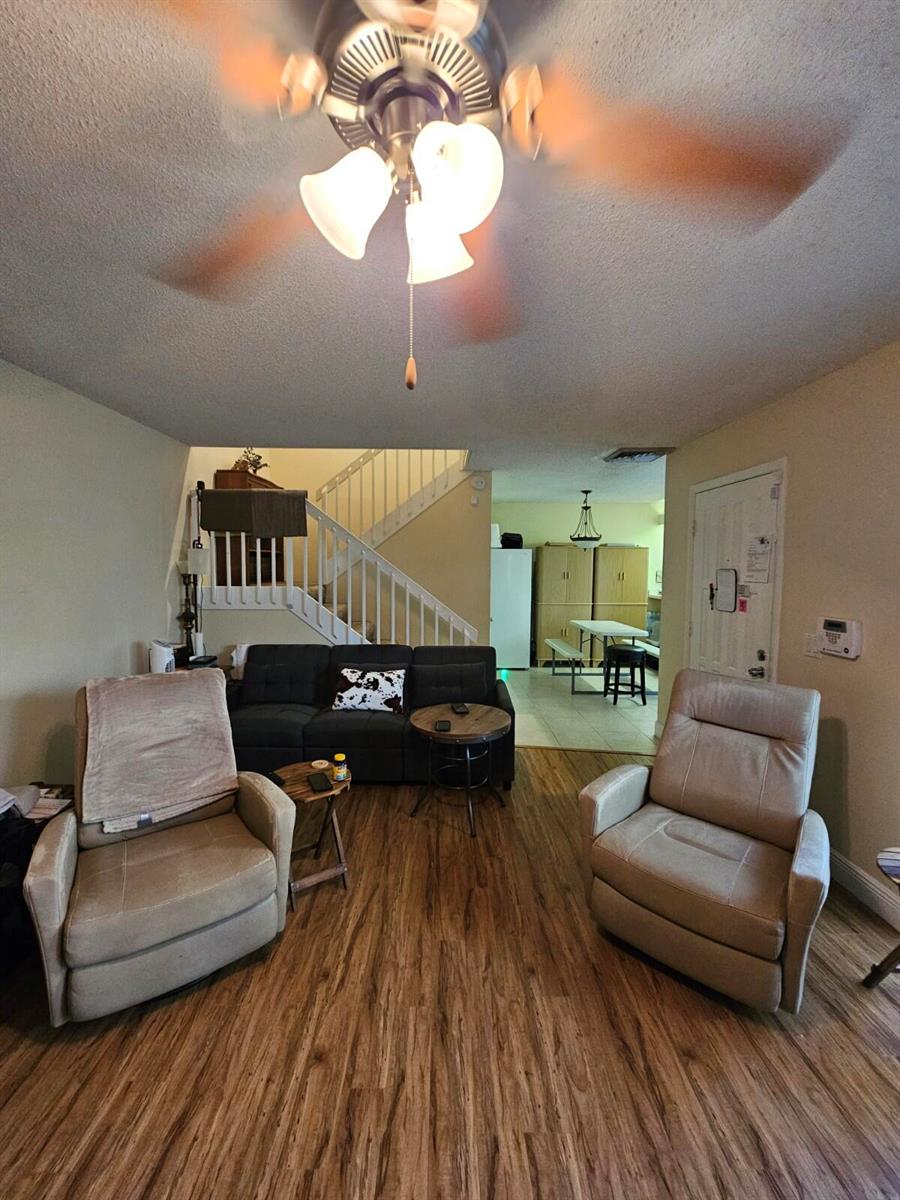 A living room features two beige recliners, a dark sofa, and wood-look flooring — 209 Charter Way, West Palm Beach FL 33407, WEST PALM BEACH, FL