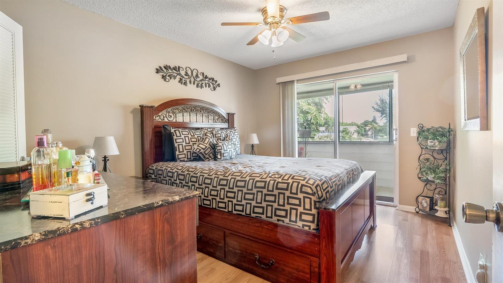 A bedroom features a wooden bed frame, a marble-topped dresser, and a sliding glass door — 239 Windsor K, West Palm Beach FL 33417, WEST PALM BEACH, FL