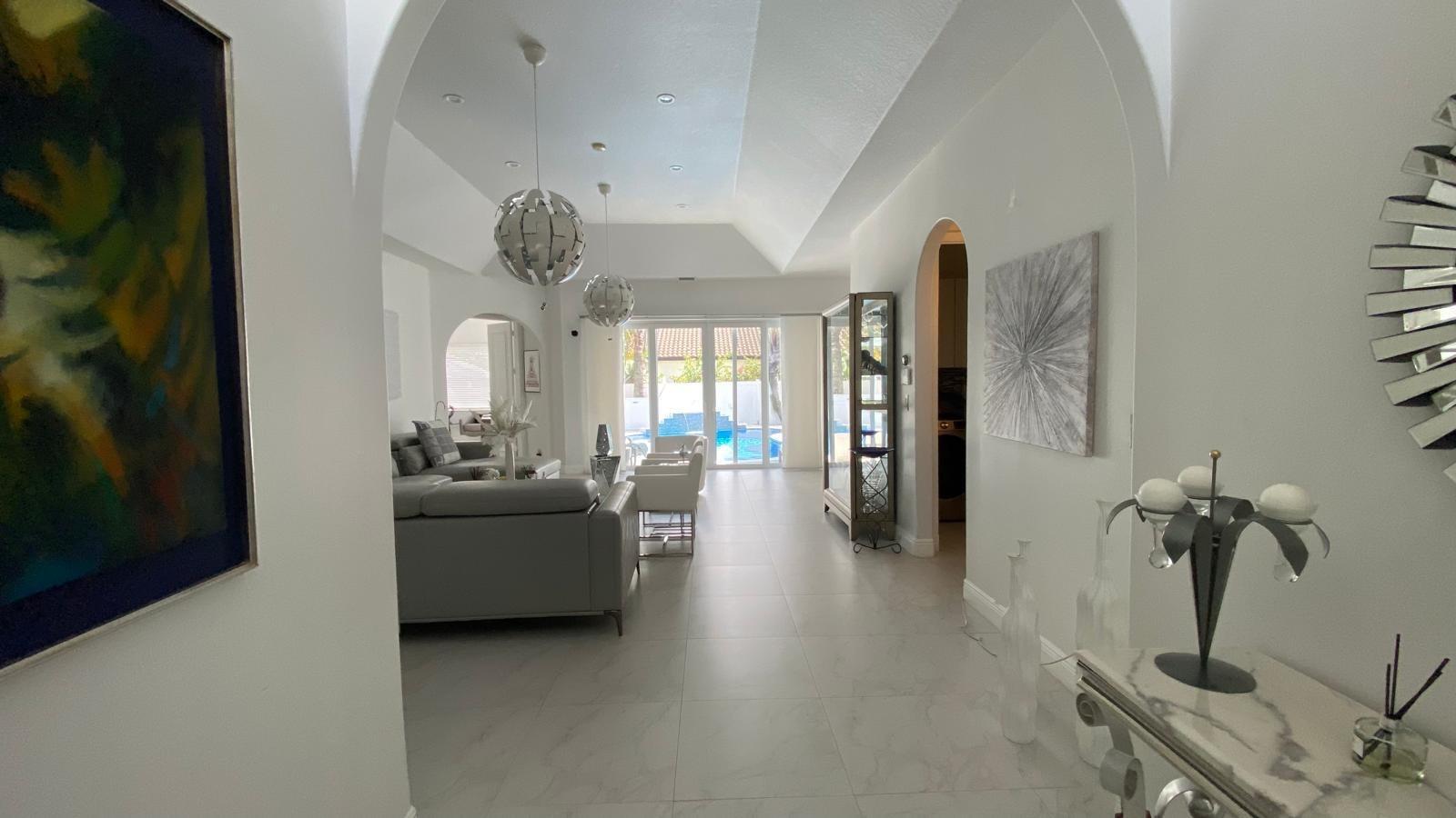 A bright entryway leads into a living room with vaulted ceilings, tile floors, and pool views — 830 Bailey Street, Boca Raton FL 33487, BOCA RATON, FL