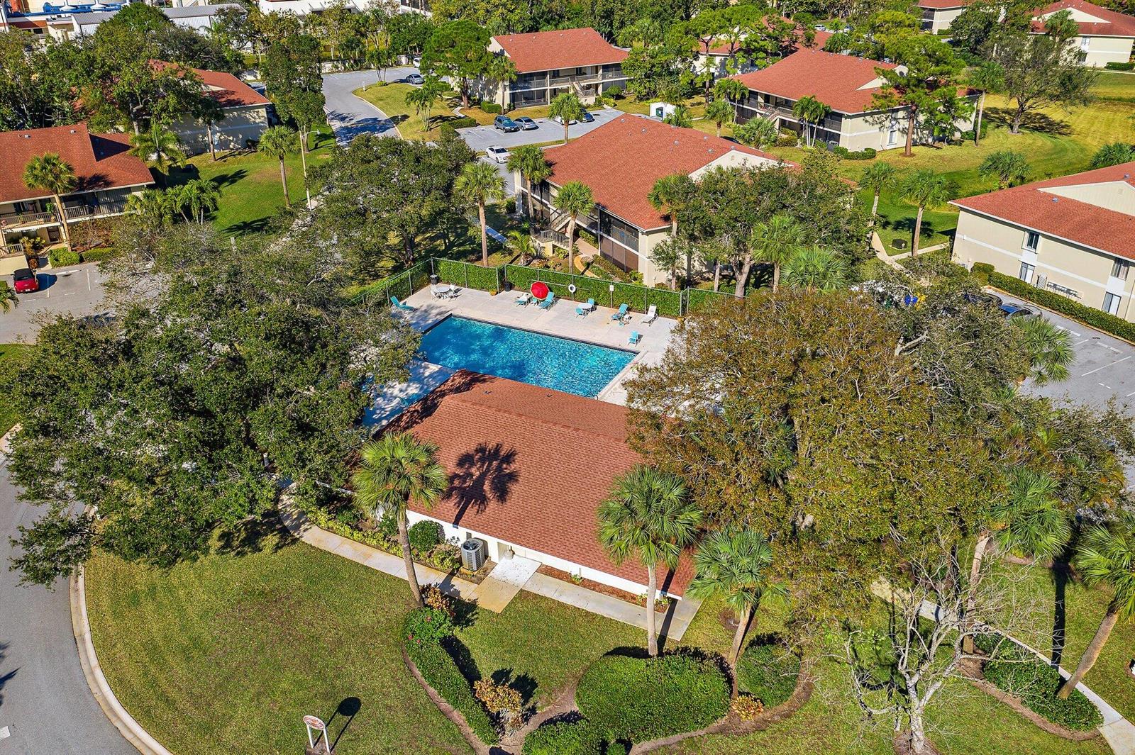 An aerial view shows a community pool surrounded by apartment buildings and lush landscaping — 6531 Chasewood Drive # H, Jupiter FL 33458, JUPITER, FL