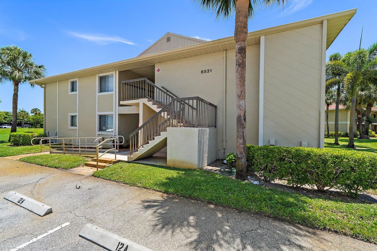 A two-story apartment building features an exterior staircase, a wheelchair ramp, and palm trees — 6531 Chasewood Drive # H, Jupiter FL 33458, JUPITER, FL