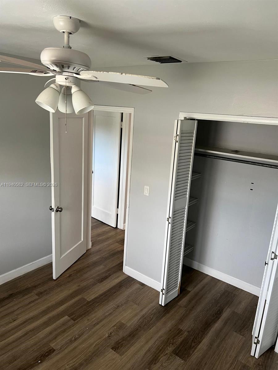 A bedroom features gray walls, wood-look flooring, a ceiling fan, and an open closet — 130 NE 171st Ter, Miami FL 33162, MIAMI, FL