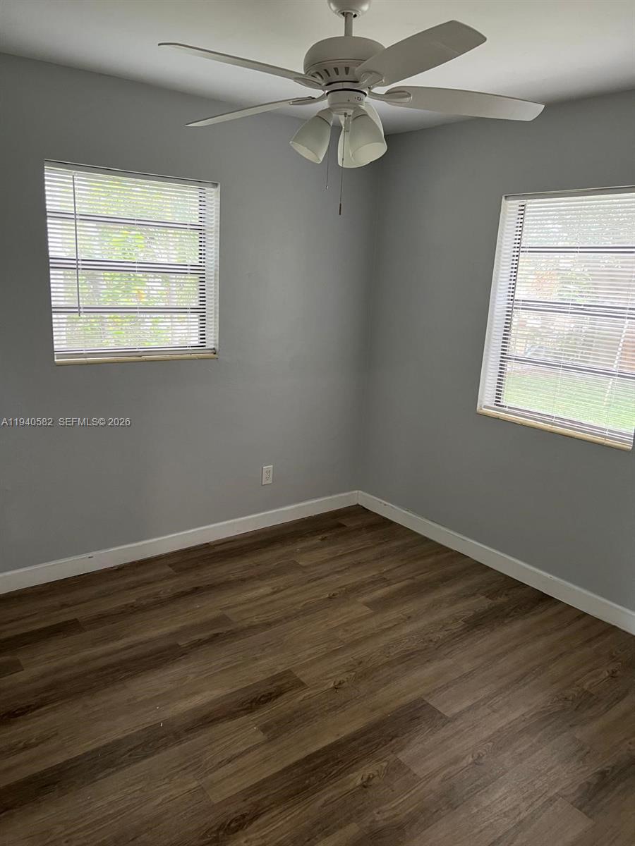 A bedroom features gray walls, wood-look flooring, a ceiling fan, and two windows with blinds — 130 NE 171st Ter, Miami FL 33162, MIAMI, FL
