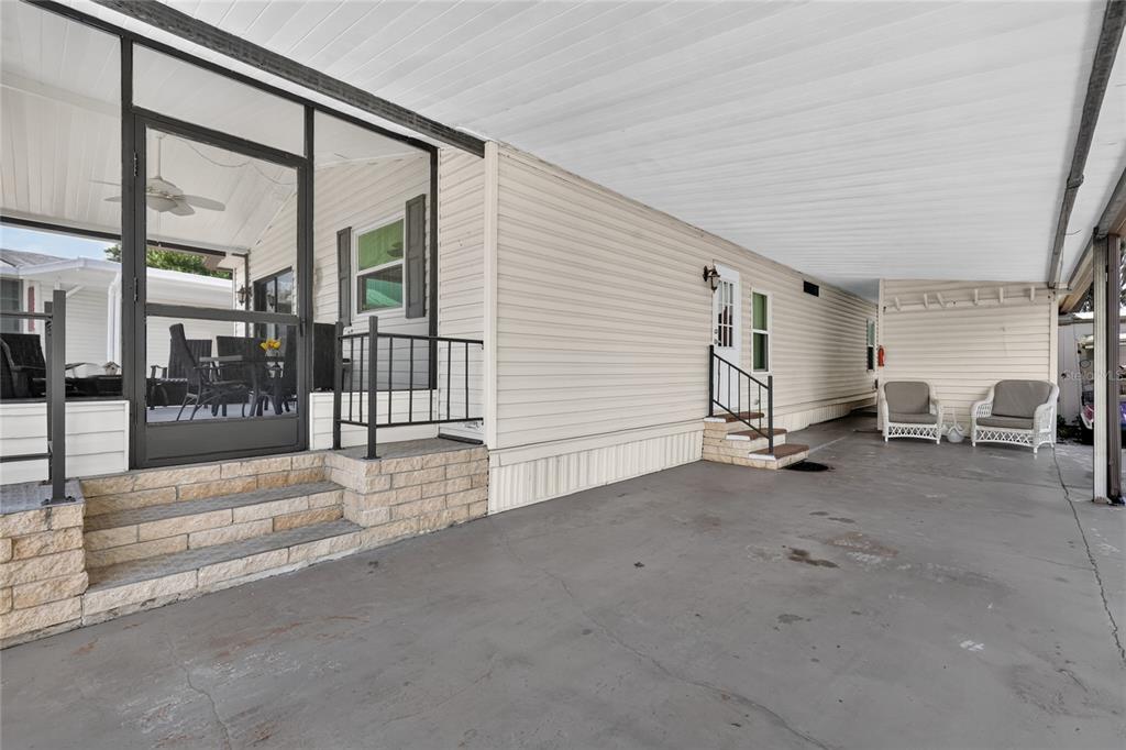 A concrete carport leads to a screened-in porch and a side entrance with stairs — 572 TAMMI DRIVE, LEESBURG, FL