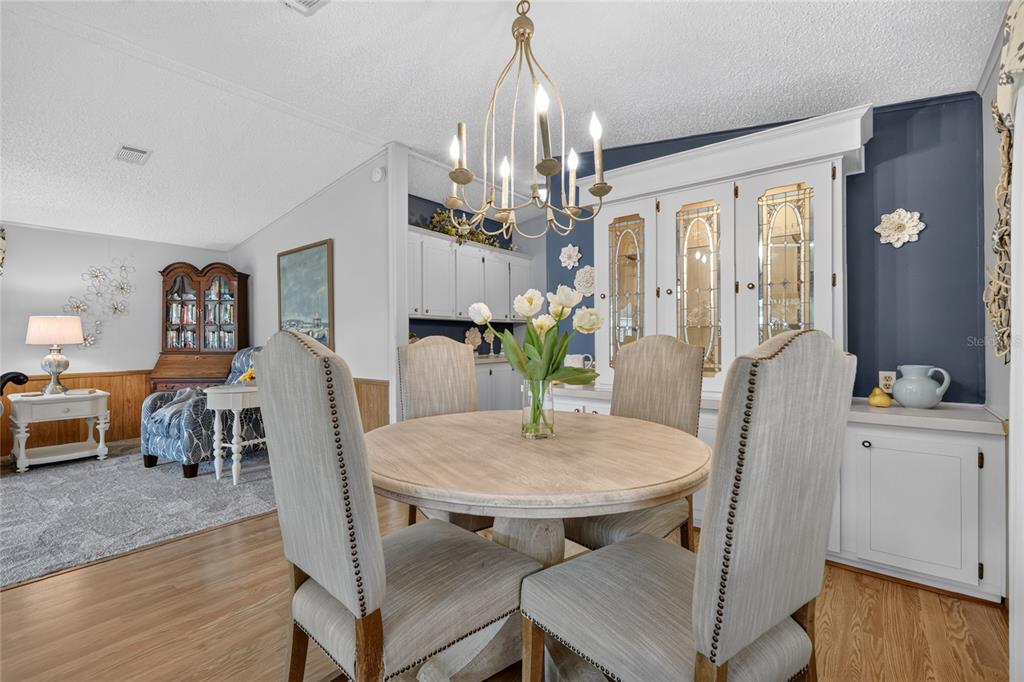 A dining area features a round wooden table, upholstered chairs, and a built-in china cabinet — 572 TAMMI DRIVE, LEESBURG, FL