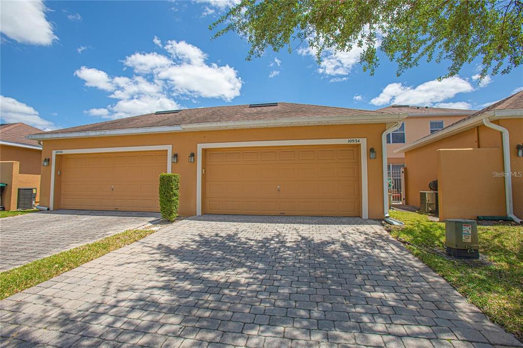 A view of a tan duplex with two garage doors and a paved driveway — 10934 SAVANNAH LANDING CIRCLE, ORLANDO, FL