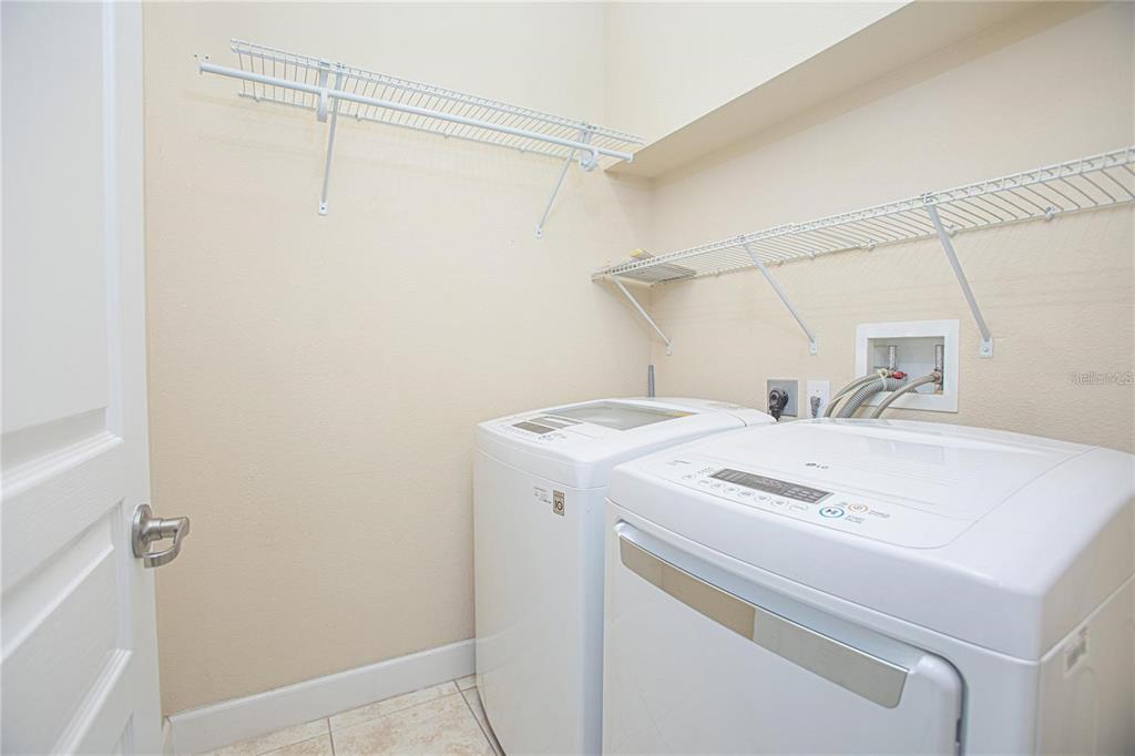 A laundry room featuring white appliances, wire shelving, and light-colored tile flooring — 10934 SAVANNAH LANDING CIRCLE, ORLANDO, FL