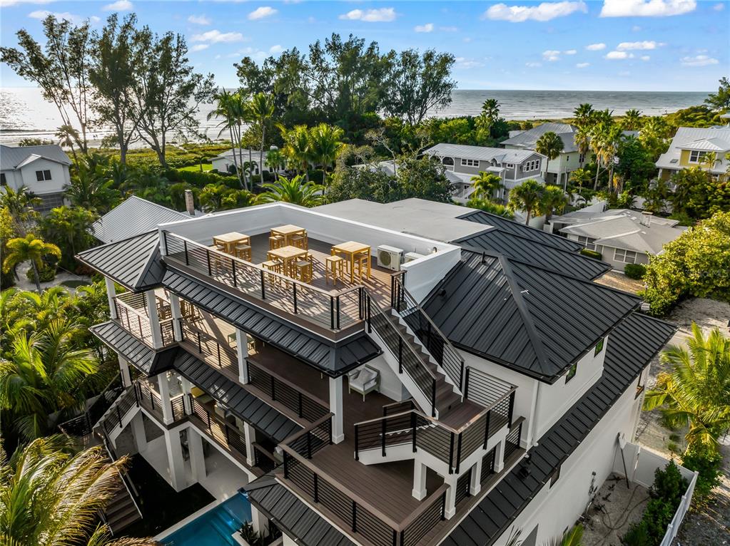 An aerial view of a multi-story coastal home featuring rooftop decks, a pool, and metal roofing — 107 MAPLE AVENUE, ANNA MARIA, FL
