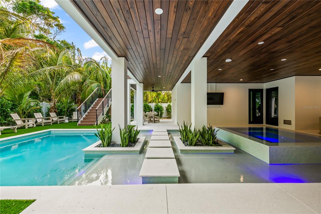A covered outdoor patio features a swimming pool, a spa, and stone stepping stones — 107 MAPLE AVENUE, ANNA MARIA, FL