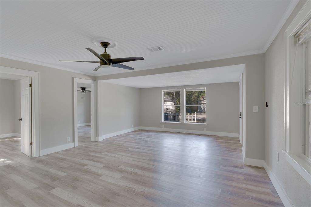 A bright living room features light wood-look flooring, a ceiling fan, and white trim — 1579 S WASHINGTON AVENUE, CLEARWATER, FL