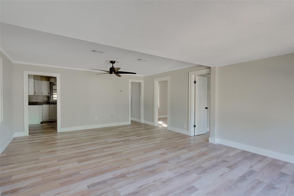 An empty living room features light gray walls, white trim, and wood-look laminate flooring — 1579 S WASHINGTON AVENUE, CLEARWATER, FL