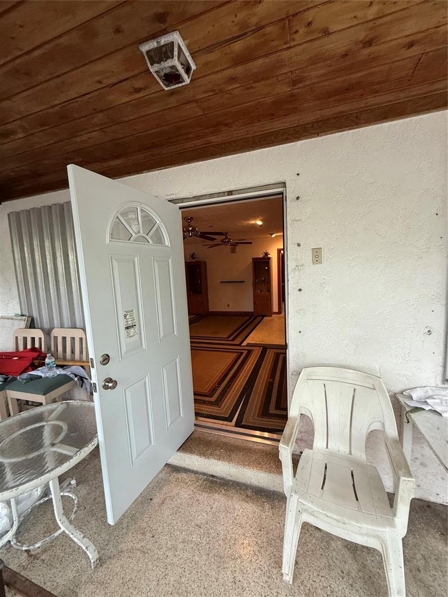 An open white door leads from a covered patio into a room with patterned carpeting — 414 Virginia Street, Key West FL 33040, KEY WEST, FL