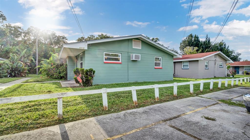 A green single-story house with a white fence and a paved driveway in front — 5526 59TH WAY N UNIT 1, ST PETERSBURG, FL
