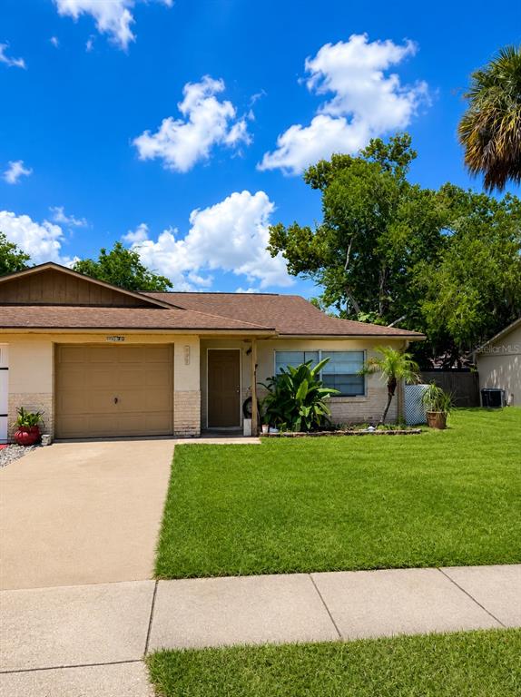 A single-story house with a tan garage, front door, and a green lawn under blue skies — 920 BOULDER DRIVE, SOUTH DAYTONA, FL