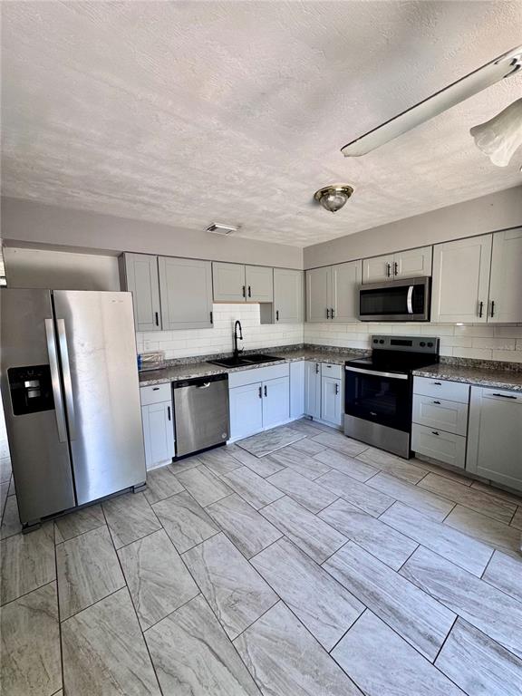 A kitchen features light gray cabinets, stainless steel appliances, and wood-look tile flooring — 920 BOULDER DRIVE, SOUTH DAYTONA, FL