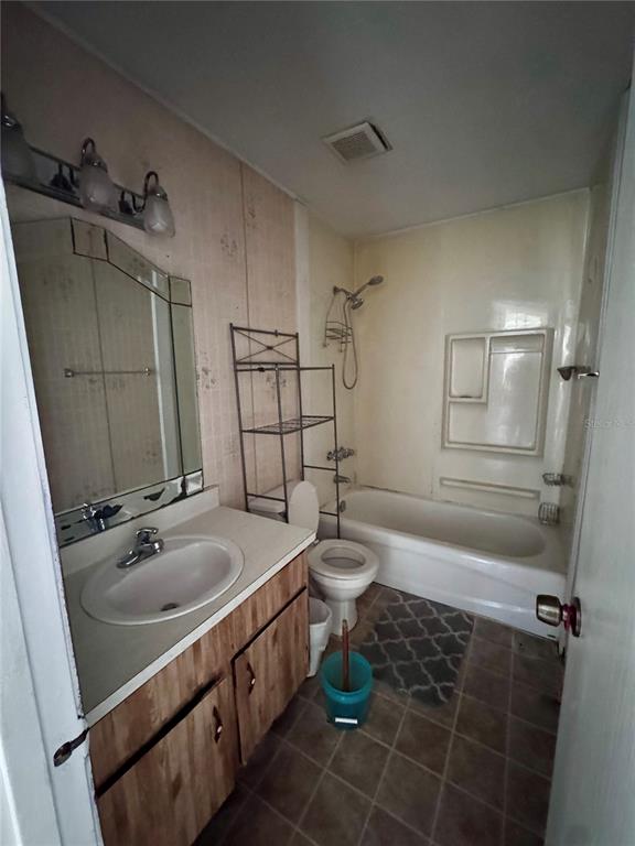 A bathroom features a wood vanity, a mirror, a toilet, and a shower-tub combination — 920 BOULDER DRIVE, SOUTH DAYTONA, FL