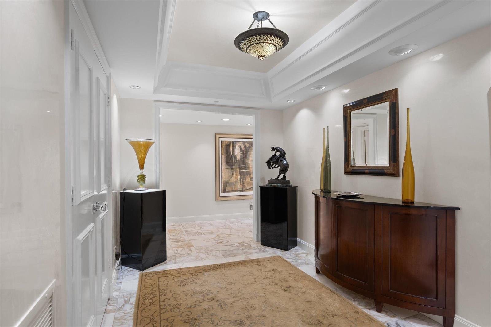 A marble-floored foyer features a tray ceiling, a dark wood console table, and pedestal displays — 2580 S Ocean Boulevard, Palm Beach FL 33480, PALM BEACH, FL