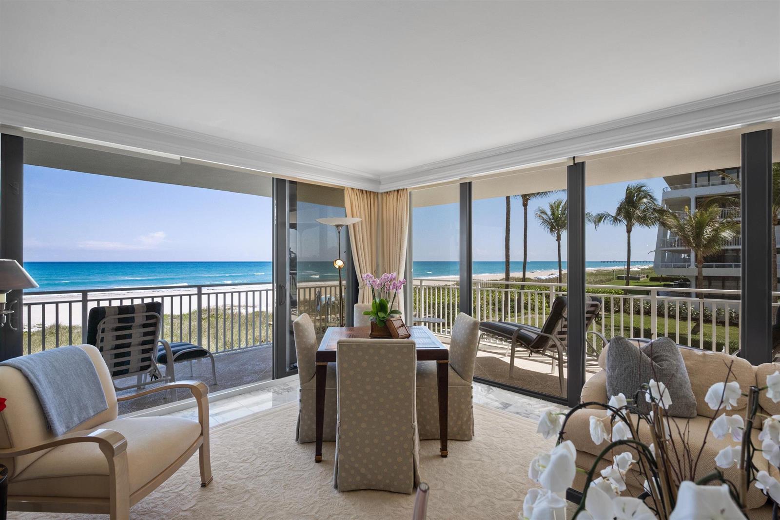 A dining area with a table and chairs overlooks the ocean through floor-to-ceiling glass doors — 2580 S Ocean Boulevard, Palm Beach FL 33480, PALM BEACH, FL