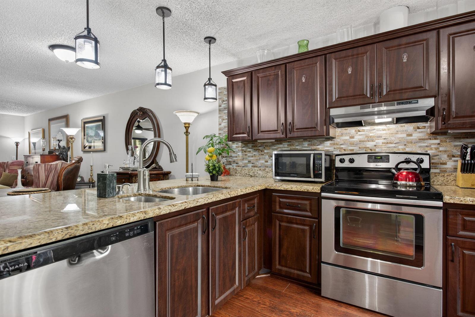 A kitchen with dark wood cabinets, granite countertops, stainless steel appliances, and a tile backsplash — 2122 NE 44th Street, Lighthouse Point FL 33064, LIGHTHOUSE POINT, FL