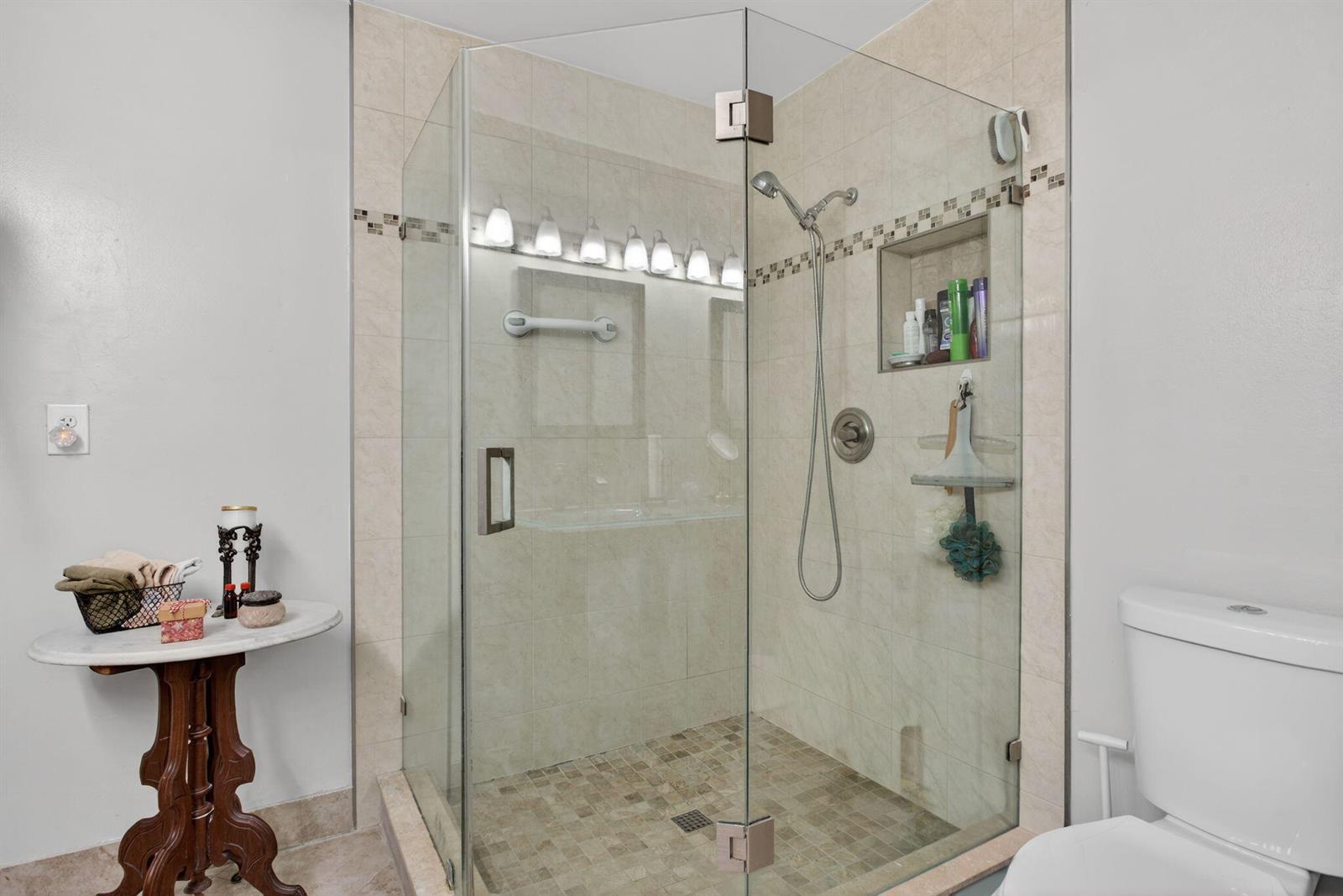 A bathroom features a glass-enclosed corner shower with beige tile and a marble-topped side table — 2122 NE 44th Street, Lighthouse Point FL 33064, LIGHTHOUSE POINT, FL