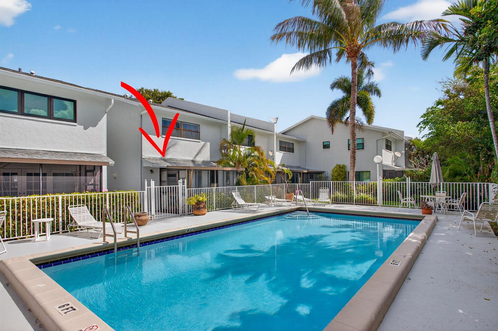 A swimming pool sits in front of a multi-story townhouse complex with a red arrow — 2122 NE 44th Street, Lighthouse Point FL 33064, LIGHTHOUSE POINT, FL