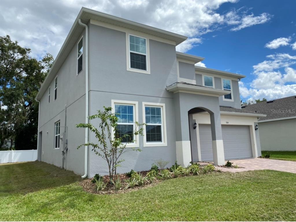 A two-story gray house with a two-car garage and a small front garden — 924 AVENAL LANE, DAVENPORT, FL