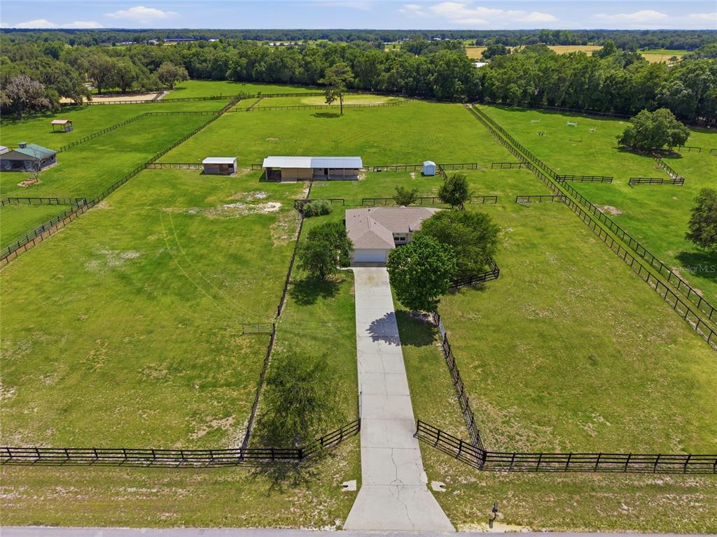 An aerial view shows a house with a long driveway surrounded by fenced pastures — 19630 SE 15TH PLACE, MORRISTON, FL