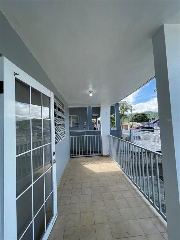 A covered outdoor balcony features light-colored floor tiles, a white metal railing, and a glass door — 3 GUARAGUAO WARD, PARCEL 206, GUAYNABO, PR