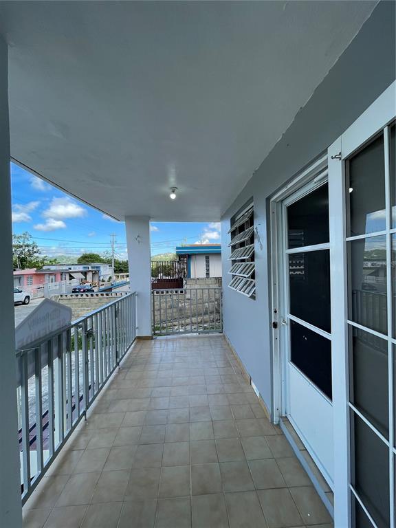 A covered balcony with tiled flooring, a metal railing, and a white door — 3 GUARAGUAO WARD, PARCEL 206, GUAYNABO, PR