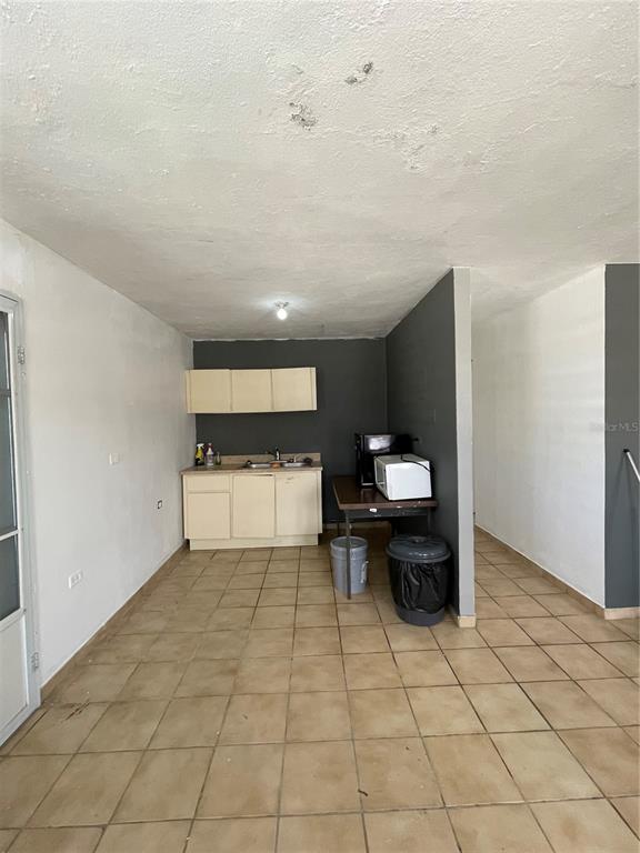 A small kitchen area features beige cabinets, a table with a microwave, and tiled flooring — 3 GUARAGUAO WARD, PARCEL 206, GUAYNABO, PR