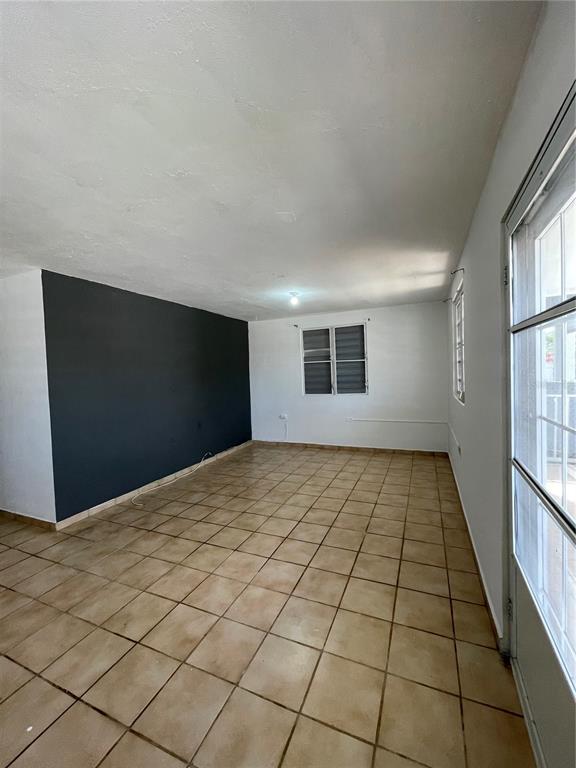 An empty room features tan tile flooring, white walls, and one dark accent wall — 3 GUARAGUAO WARD, PARCEL 206, GUAYNABO, PR