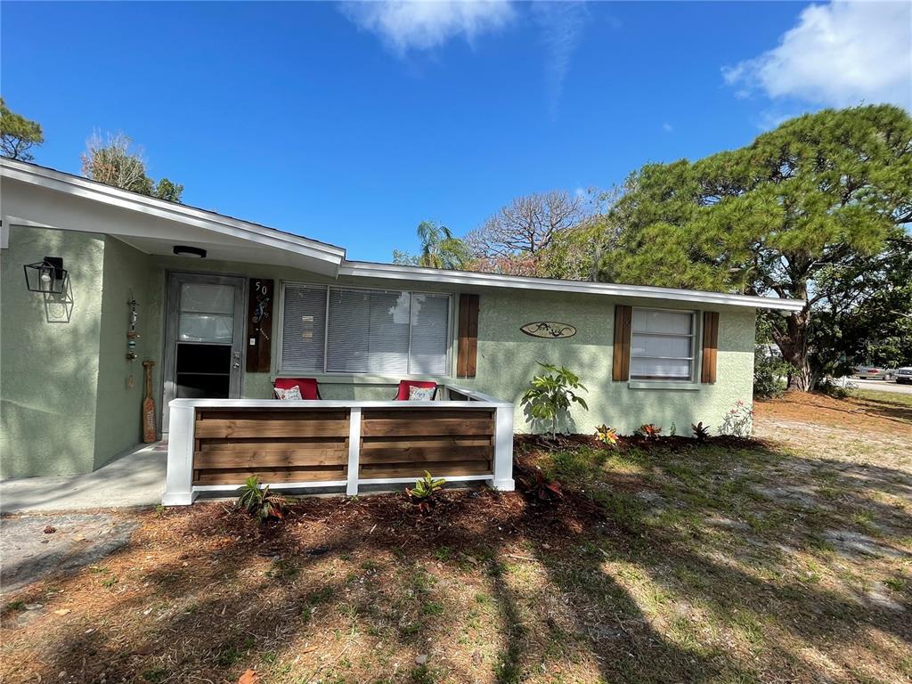 A light green house features a wooden porch railing and a front door with a window — 50 EUCLID AVENUE, ENGLEWOOD, FL