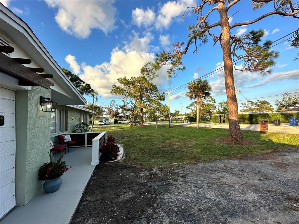 A view of a house exterior with a porch, a large lawn, and tall trees — 50 EUCLID AVENUE, ENGLEWOOD, FL