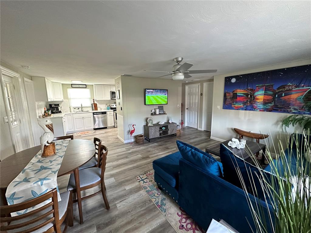 An open-concept living room and kitchen feature wood-look flooring, a blue sectional, and white cabinets — 50 EUCLID AVENUE, ENGLEWOOD, FL