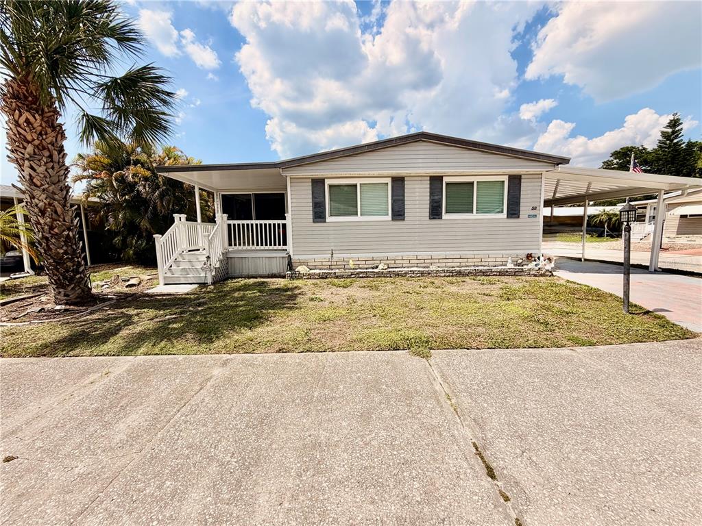 A single-story manufactured home with light gray siding, a front porch, and a carport — 1710 7TH STREET SW UNIT 50, RUSKIN, FL