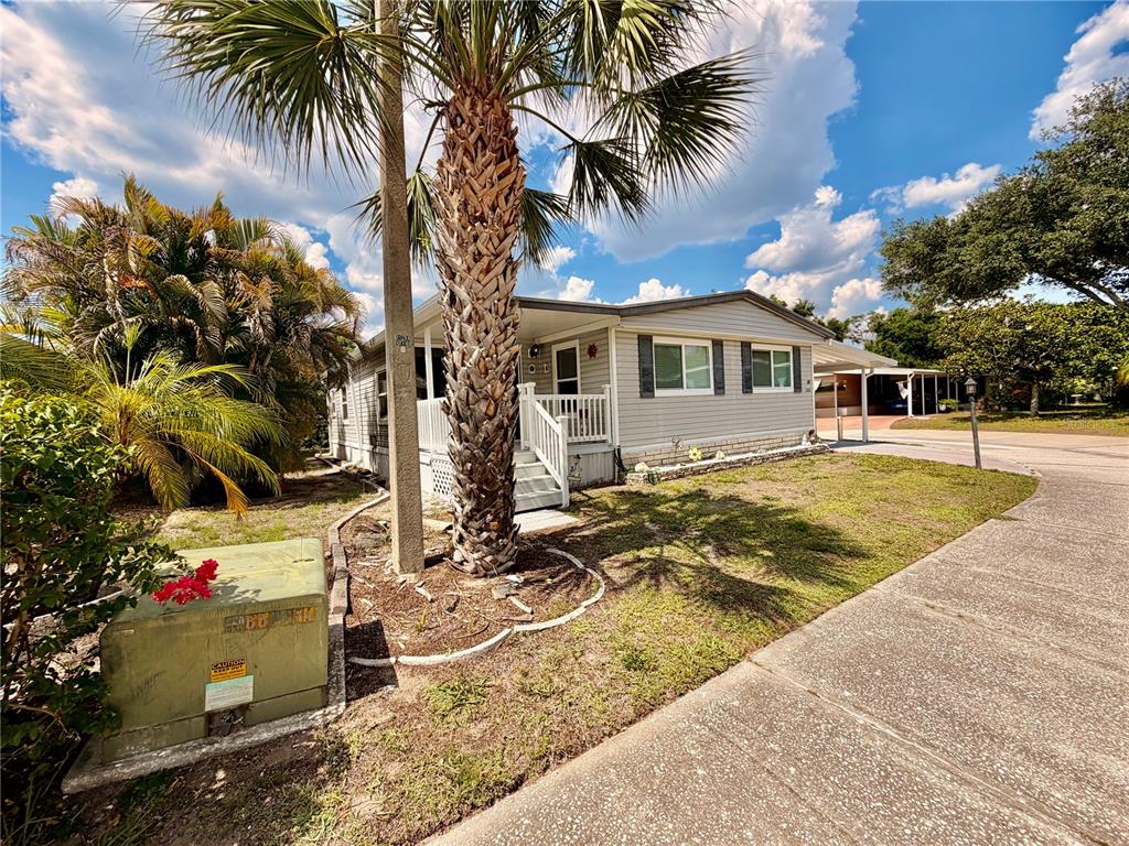 A light gray manufactured home with a front porch and a palm tree in the yard — 1710 7TH STREET SW UNIT 50, RUSKIN, FL
