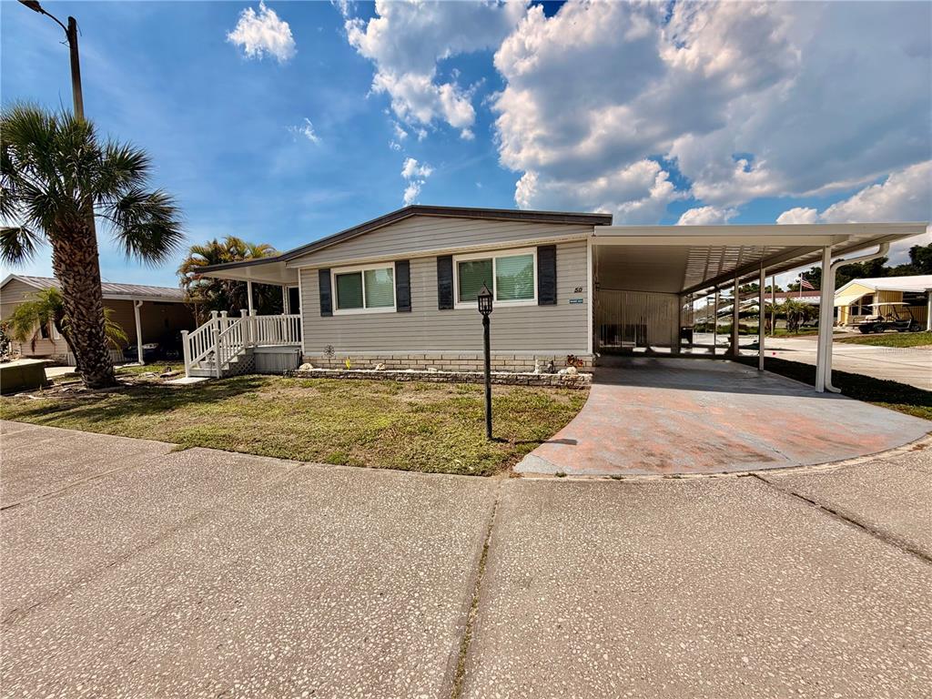 A single-story manufactured home with light gray siding, a carport, and a front porch — 1710 7TH STREET SW UNIT 50, RUSKIN, FL