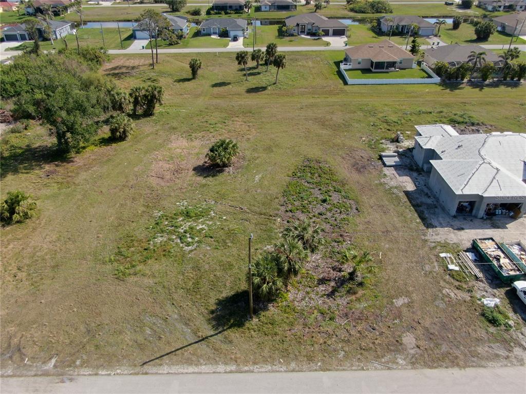 An aerial view shows a vacant residential lot with scattered palm trees and nearby houses — 185 ROTONDA BOULEVARD S, ROTONDA WEST, FL