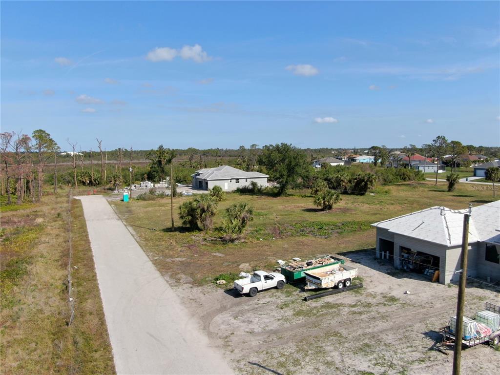 An aerial view shows a gravel road leading to a house under construction with building materials — 185 ROTONDA BOULEVARD S, ROTONDA WEST, FL