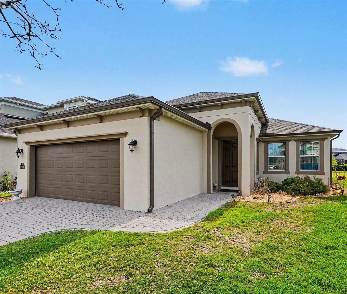 A single-story house with a beige stucco exterior, a two-car garage, and a paved walkway — 2964 Blazing Star Drive, Melbourne FL 32940, MELBOURNE, FL