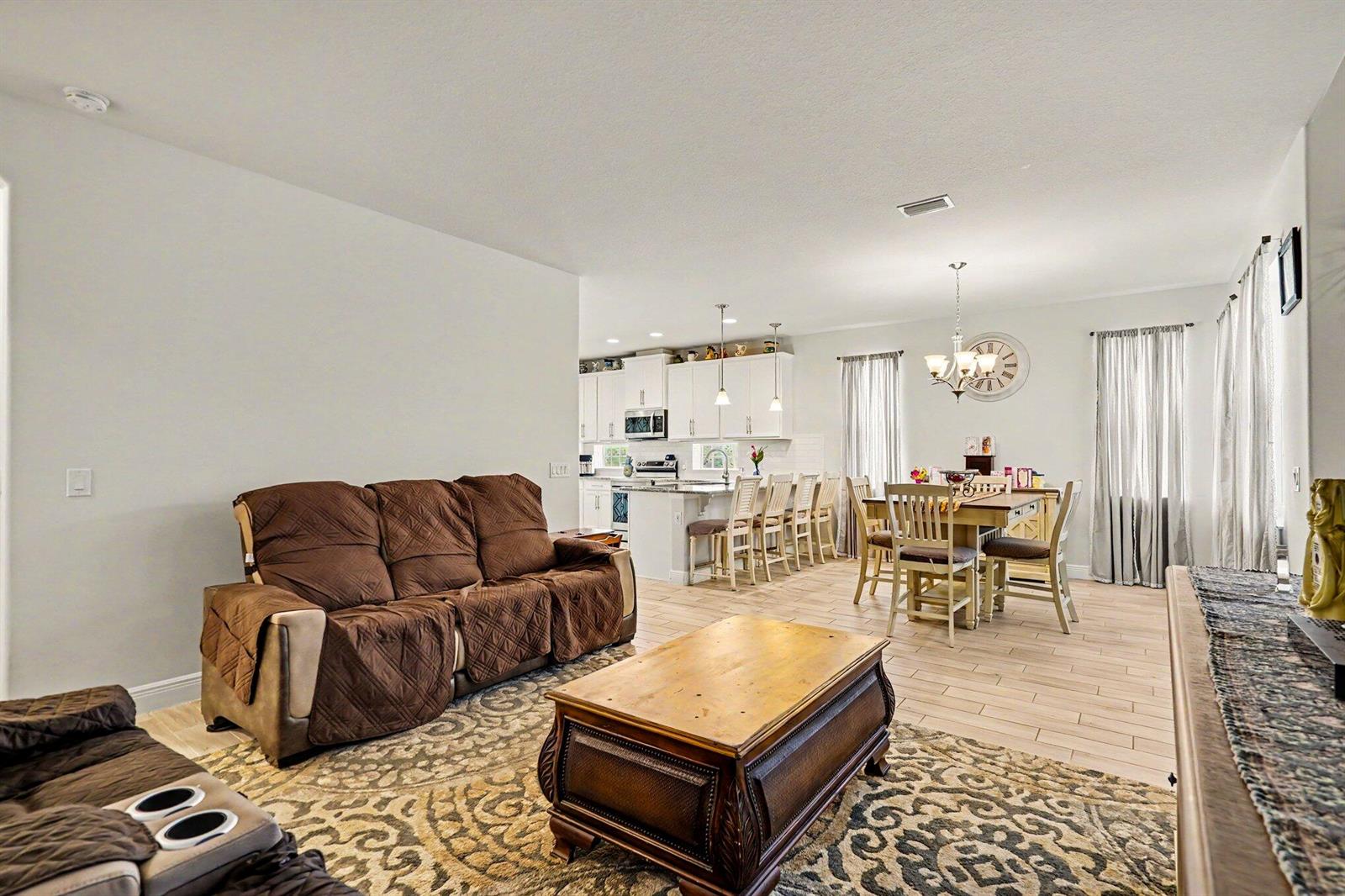 An open-concept living room and dining area with tile flooring and a kitchen in back — 2964 Blazing Star Drive, Melbourne FL 32940, MELBOURNE, FL